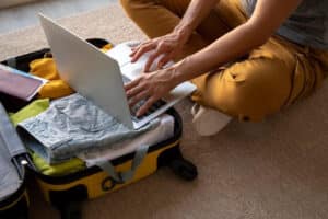 viaggiatore che fa selfcheck-in con computer su valigia aperta